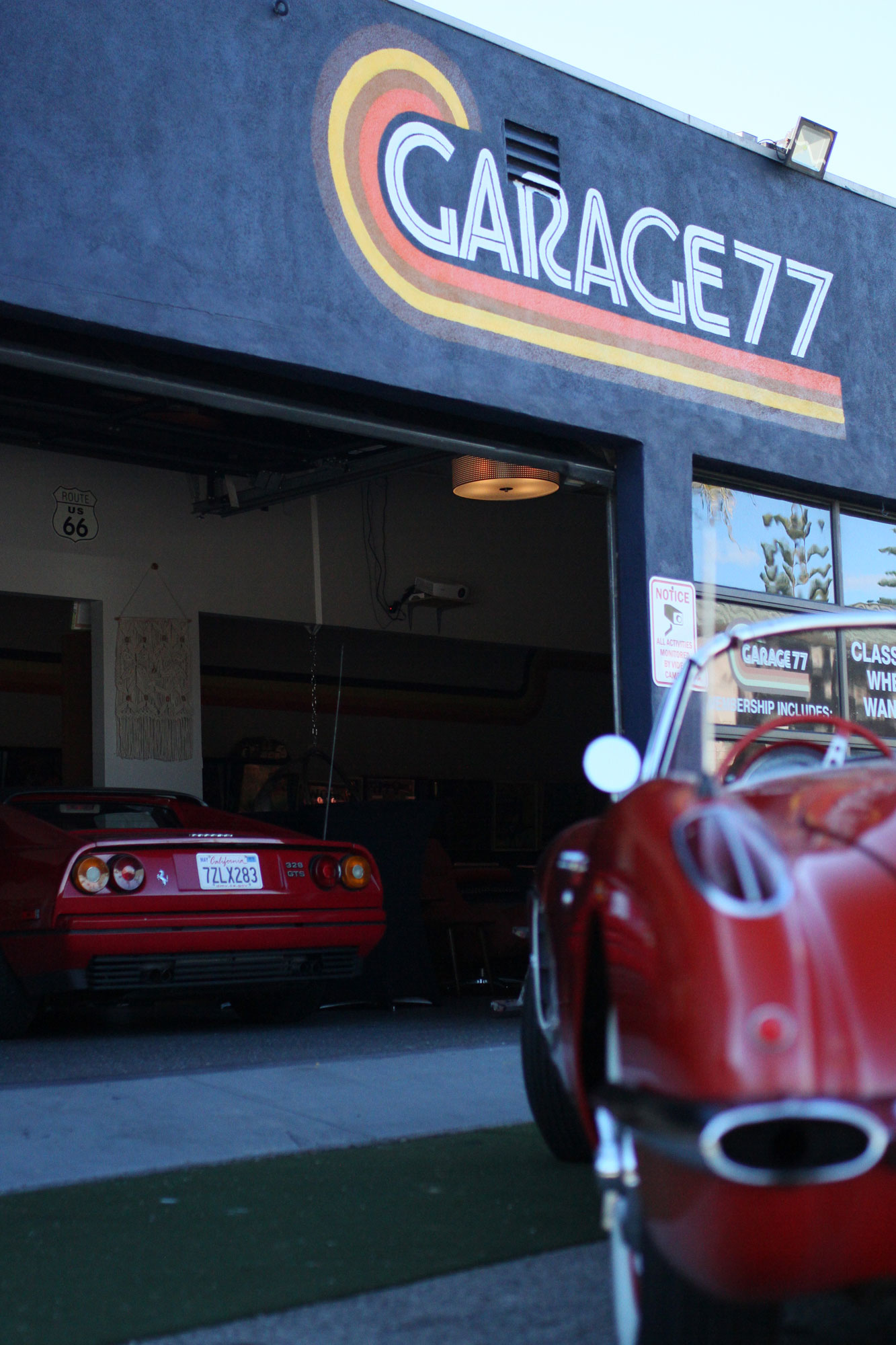 The red Ferrari 328 GTSi and the Corvette C1 inside and outside the Garage 77