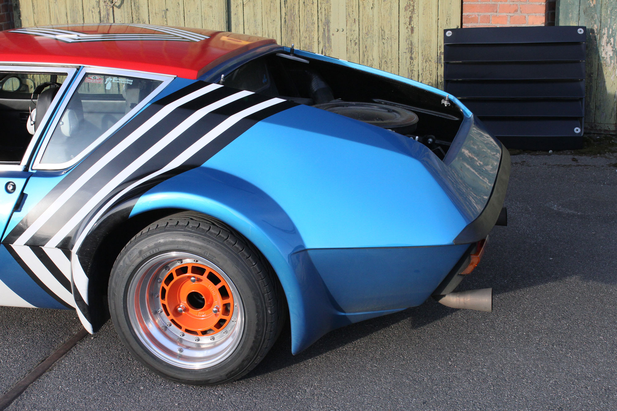 Left behind with the engine hatch of and standing against the wall, while the Renault Alpine A310 is standing in the sun